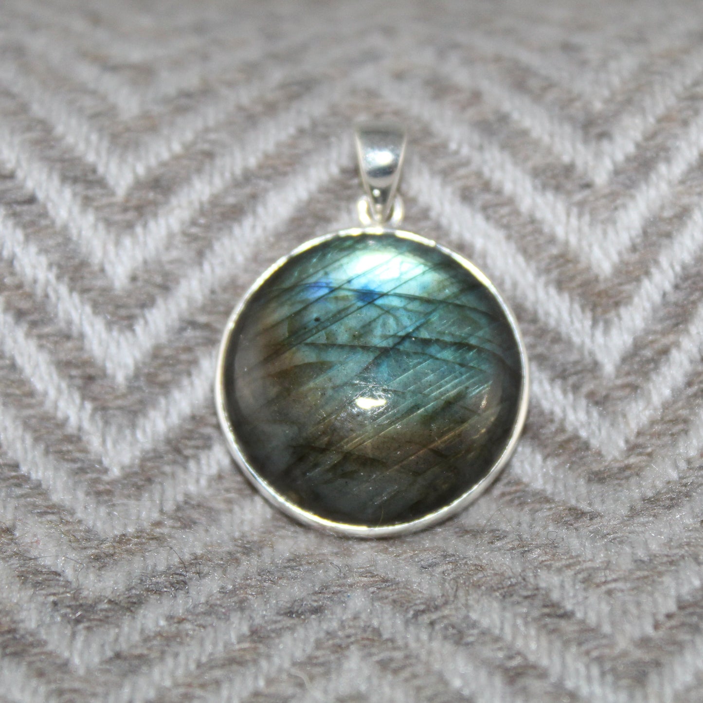 Labradorite pendant in silver against a herringbone patterned fabric background