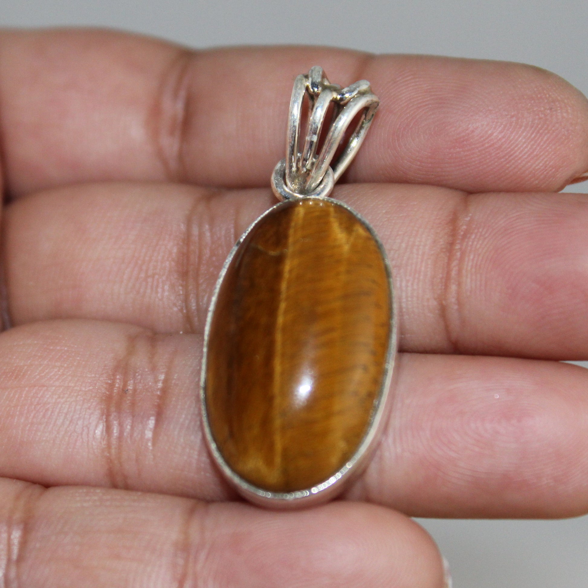 Tiger's eye pendant on a hand with a neutral background