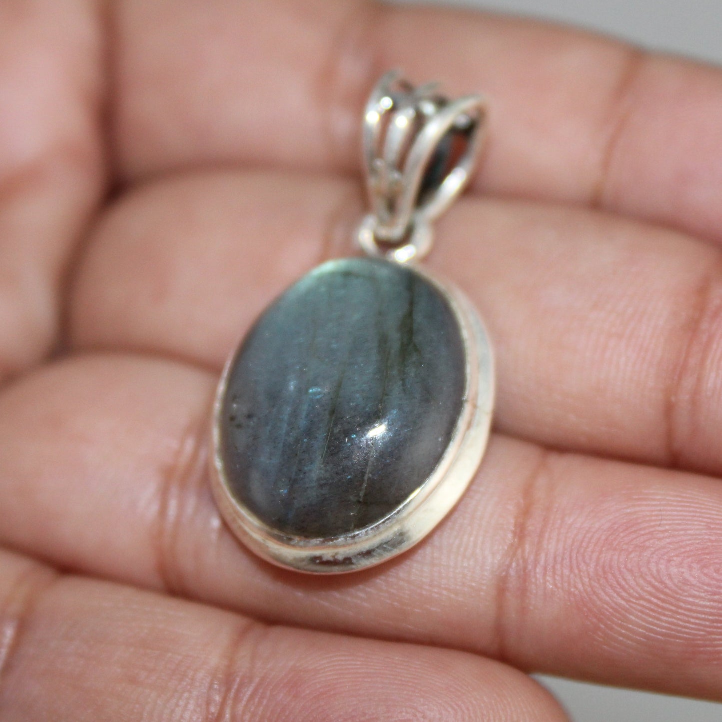 Labradorite pendant on a hand with a neutral background