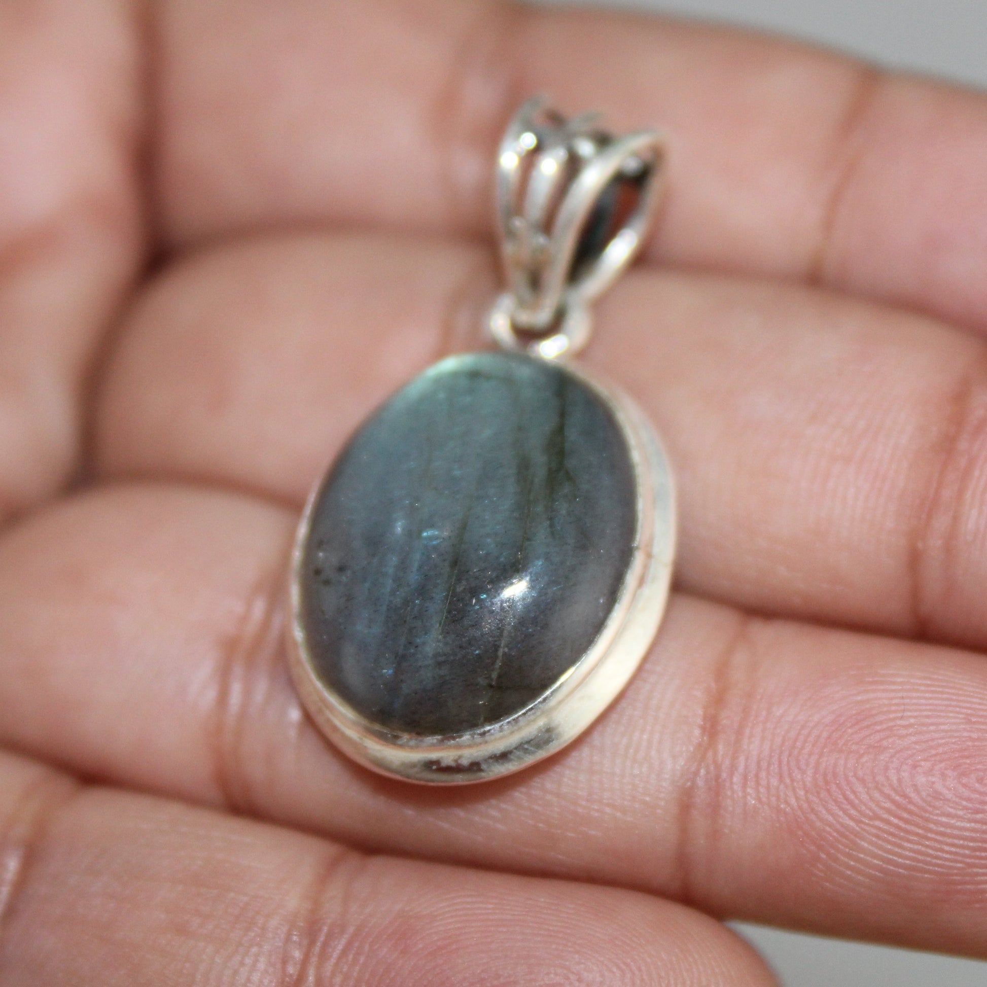 Labradorite pendant on a hand with a neutral background