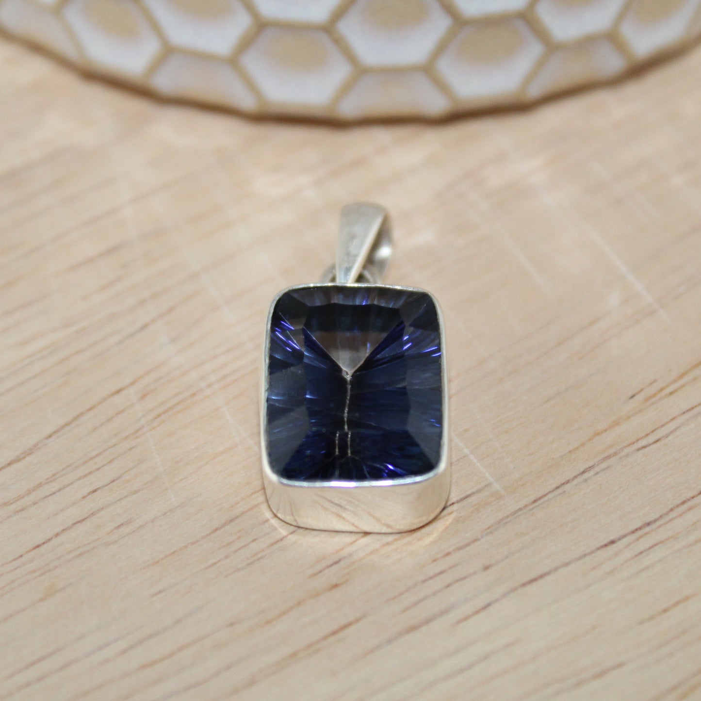 Silver pendant with a blue gemstone on a wooden surface