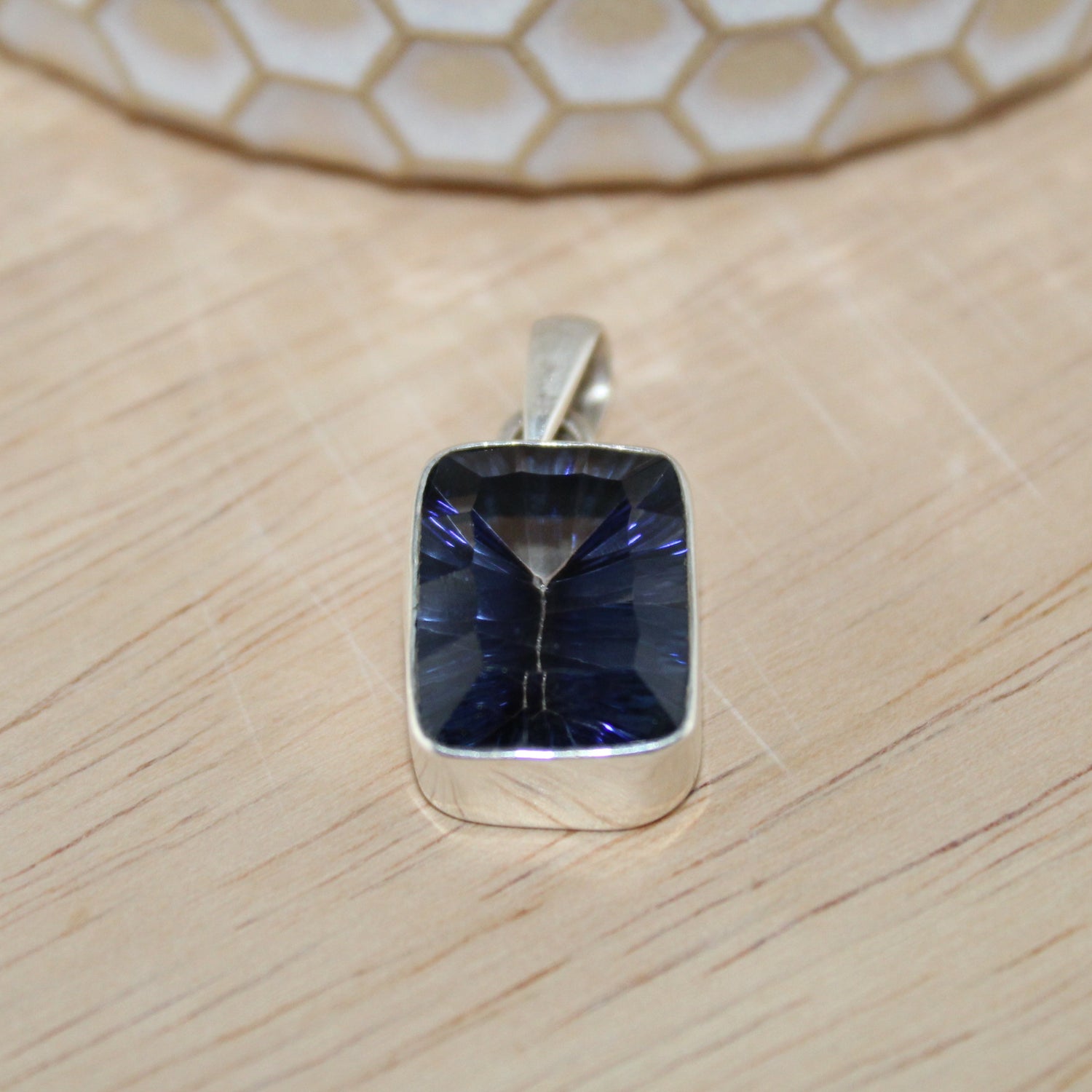 Silver pendant with a blue gemstone on a wooden surface
