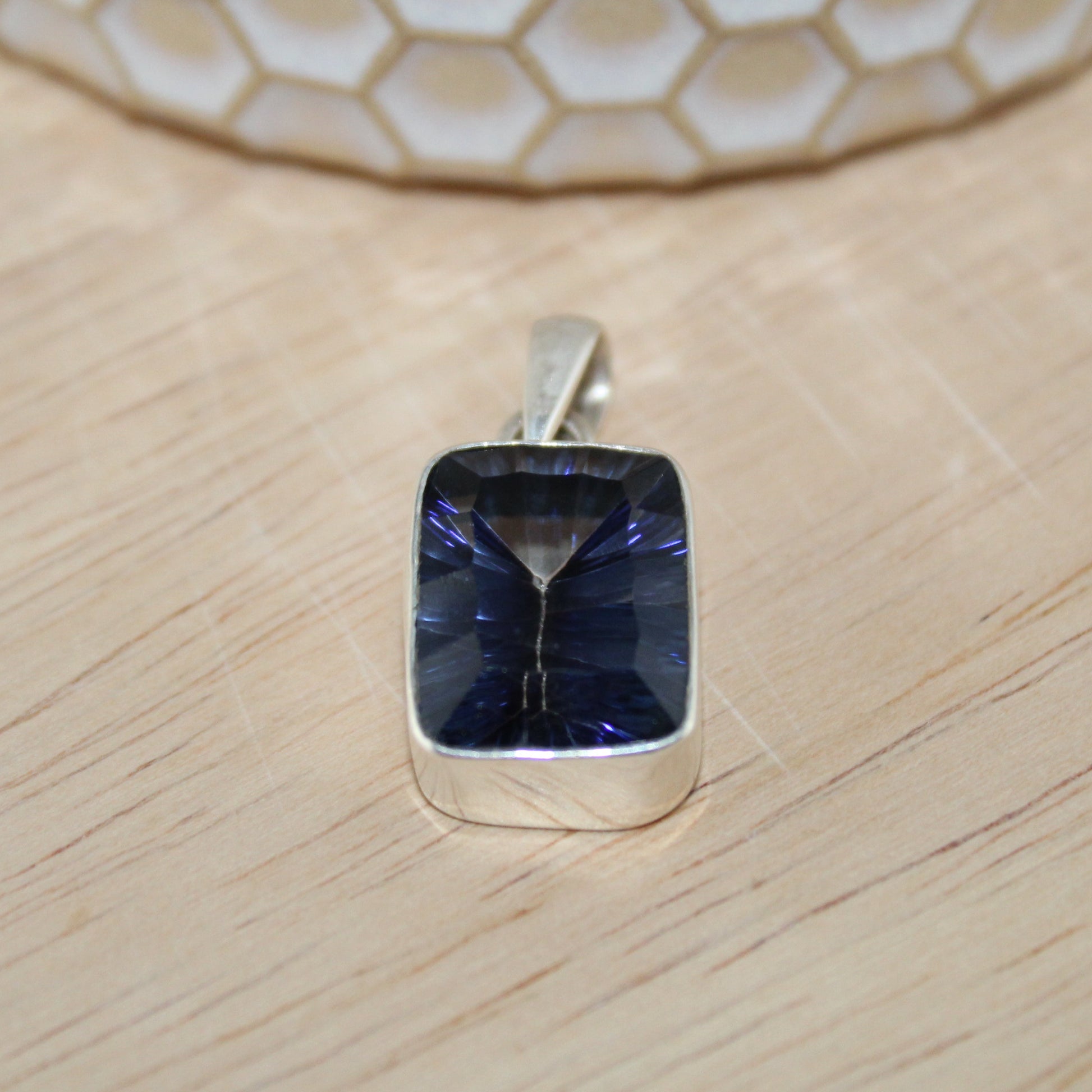 Silver pendant with a blue gemstone on a wooden surface