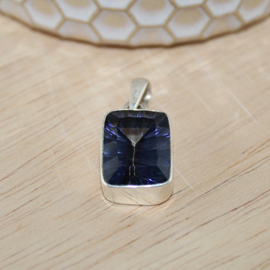 Silver pendant with a blue gemstone on a wooden surface