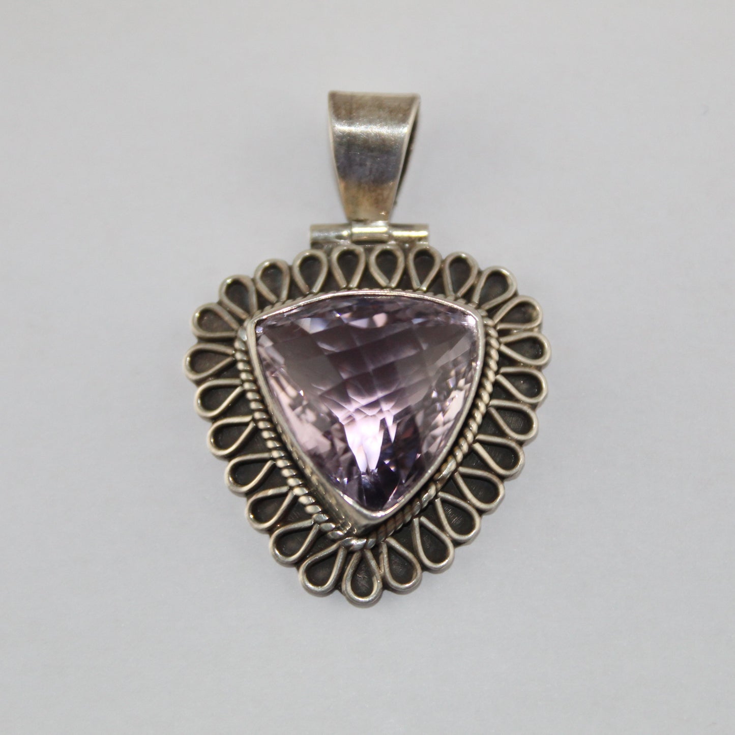 Silver pendant with a purple gemstone on a gray background