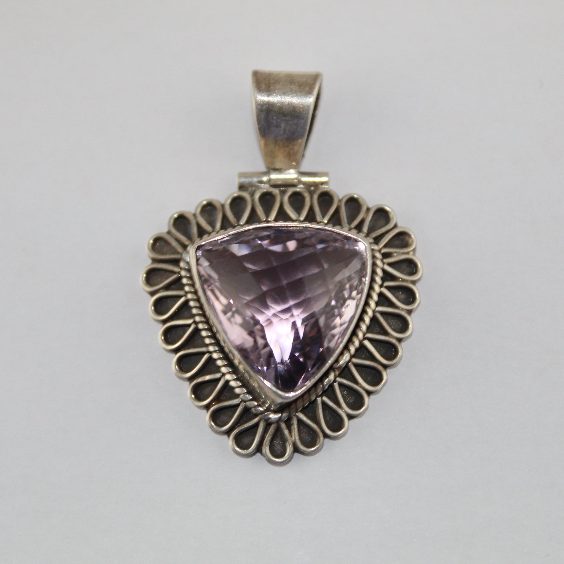 Silver pendant with a purple gemstone on a gray background