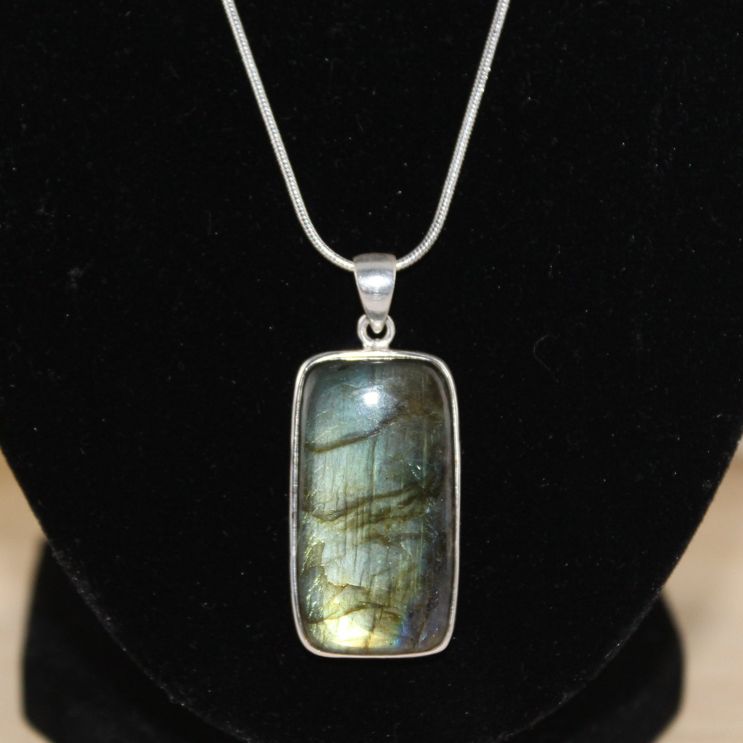 Labradorite pendant on a black stand with a blurred background