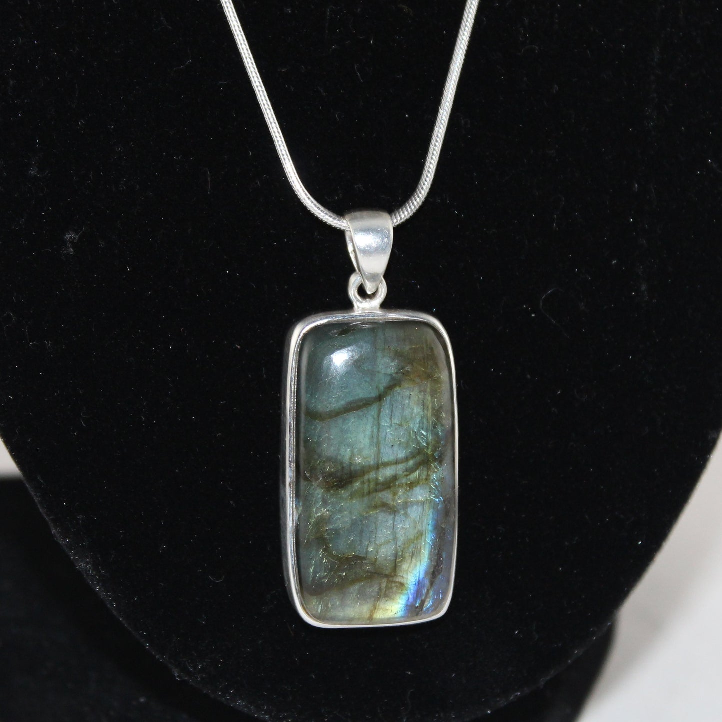 Labradorite pendant on a silver chain against a black background